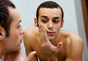 Man checking face and hairline in mirror